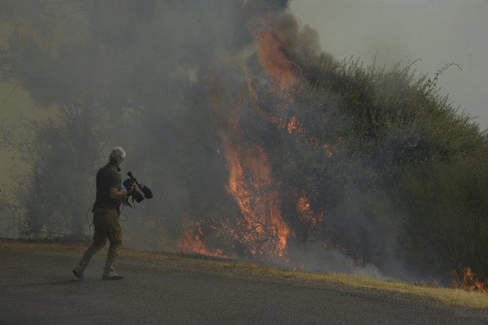 Una persona con cámara de vídeo graba un fuego en el polígono industrial de A Rúa, a 16 de agosto de 2025, en A Rúa, Ourense, Galicia (España). Alrededor de 40 municipios se encuentran sin servicio de recogida de basuras por el incendio de Larouco, que af