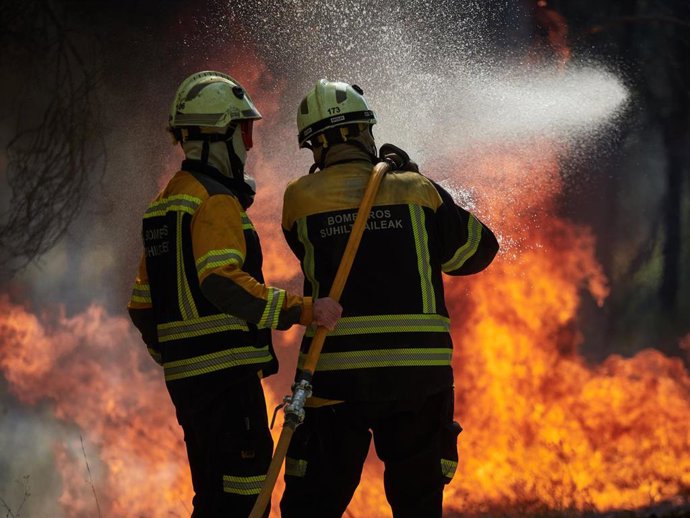 Foto de archivo de dos bomberos trabajando en la extinción del incendio de Carcastillo.