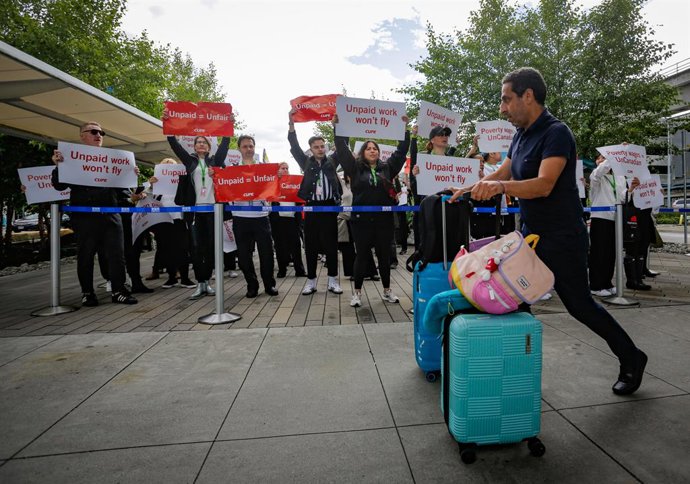PEQUIM, 17 de agosto de 2025 -- Um viajante passa por comissários de bordo em greve da Air Canada no Aeroporto Internacional de Vancouver em Richmond, Colúmbia Britânica, Canadá, em 16 de agosto de 2025.   A maior companhia aérea do Canadá, a Air Canada, 