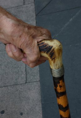 Archivo - Una persona mayor camina por la calle ayudada por un bastón