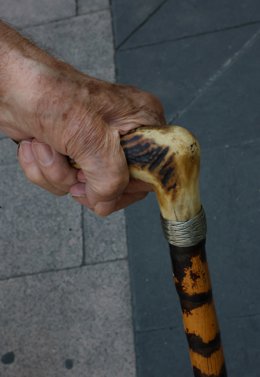 Archivo - Arxivo - Una persona major camina pel carrer ajudat per un bastó