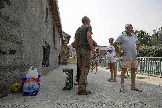 Vecinos del pueblo de Molinaferrera, confinado por la proximidad del incendio forestal, entregan bocadillos y agua a los voluntarios y bomberos, a 17 de agosto de 2025, en Molinaferrera, León, Castilla y León (España). 