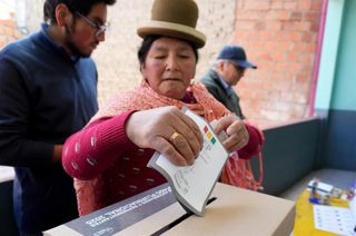 Una mujer indígena inserta su papeleta en la urna para elegir presidente en Bolivia