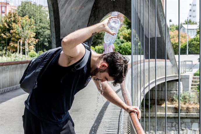 Un chico se moja la cabeza, a 12 de agosto en Madrid (España). 