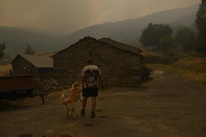 Una persona con su perro observa el incendio en Requeixo, a 11 de agosto de 2025, en Chandrexa de Queixa, Ourense, Galicia (España). 