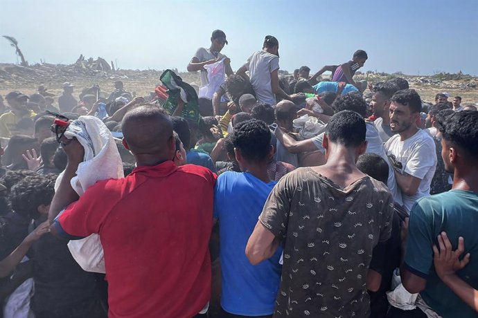 14 de agosto de 2025, Territórios Palestinos, Gaza: Palestinos correm para recuperar pacotes de ajuda lançados de paraquedas durante um lançamento aéreo sobre Nuseirat, no centro da Faixa de Gaza, em meio a uma crise de fome devido ao bombardeio e ao bloq