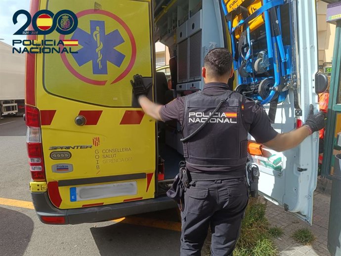 Un agente de la Policía Nacional, junto a una ambulancia