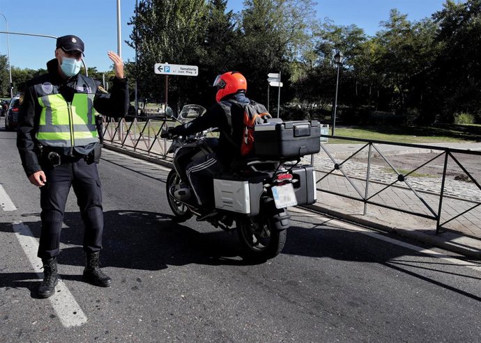 Archivo - Un policía de la Unidad de Prevención y Reacción da el paso a una moto en un control policial en la Avenida de los Poblados con la A-42 de salida de Madrid, la mañana del 3 octubre del 2020. Las medidas de restricción del Gobierno central que af