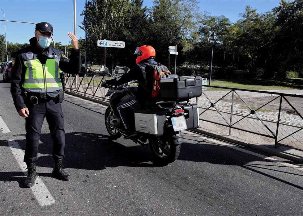 Archivo - Un policía de la Unidad de Prevención y Reacción da el paso a una moto en un control policial en la Avenida de los Poblados con la A-42 de salida de Madrid, la mañana del 3 octubre del 2020. Las medidas de restricción del Gobierno central que