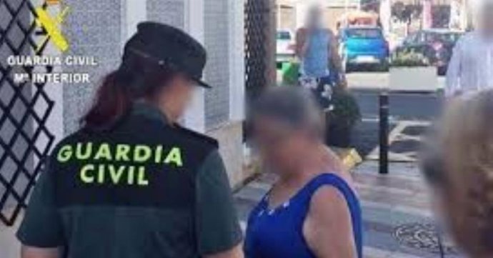 Una agente de Guardia Civil atiende a una mujer en la calle.
