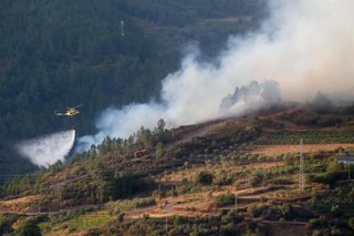 Un helicóptero colabora en las labores de extinción del incendio, a 19 de agosto de 2025, en Quiroga, Lugo, Galicia (España). El fuego amenaza la sierra de O Courel en su avance desde la localidad lucense de Quiroga lo que ha alertado a los vecinos de la 
