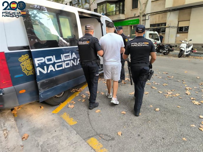 Uno de los detenidos es conducido a un furgón policial por varios agentes.