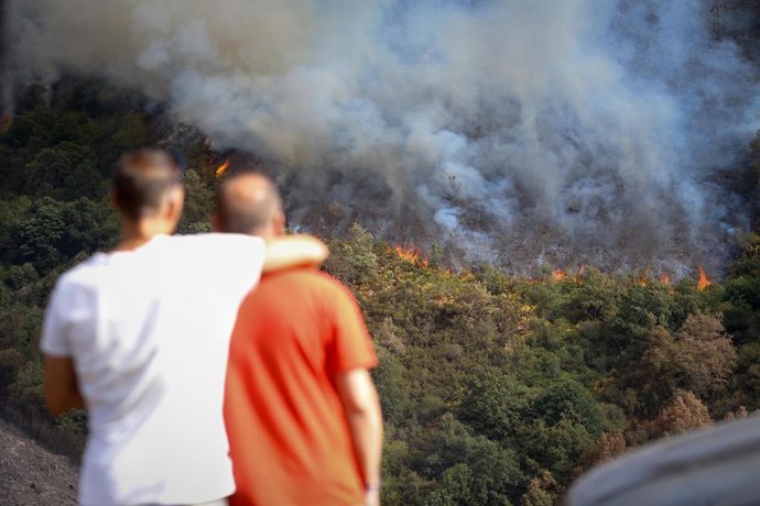 Várias pessoas observam o incêndio, na cordilheira de O Courel, em 19 de agosto de 2025, em Quiroga, Lugo, Galícia (Espanha). O incêndio está ameaçando a cordilheira de O Courel à medida que avança a partir da cidade de Quiroga, em Lugo, o que alertou os 