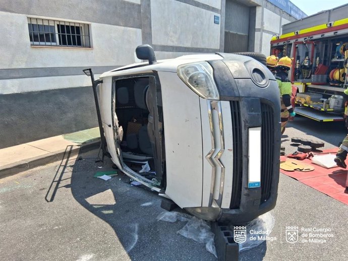 Efectivos de Bomberos y de la Policía Local intervienen tras el vuelco de un vehículo en Málaga.