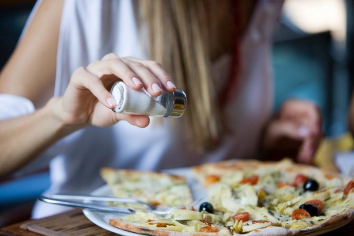 Archivo - Una mujer echando sal en su comida.