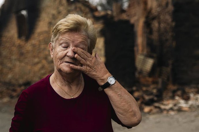 Una vecina de Castrocalbón, junto a una vivienda que ha sido destruida por los incendios.