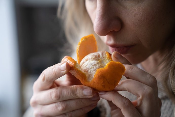 Archivo - Una mujer huele una mandarina.