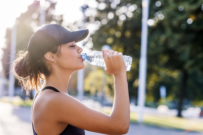 Archivo - Mujer bebiendo agua mientras hace deporte.