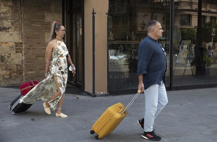 Archivo - Turistas con equipaje caminan por el centro de la ciudad. A 25 de agosto de 2021. En Sevilla (Andalucía, España).