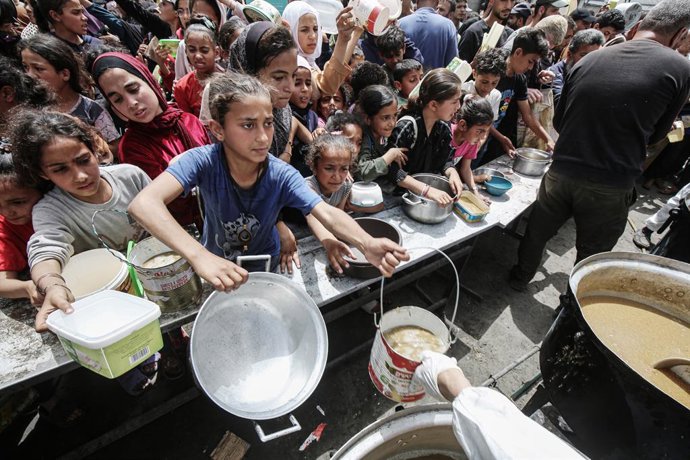 Archivo - Imagen de archivo de un grupo de palestinos esperando para recibir ayuda alimentaria en Gaza.