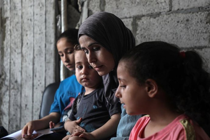 GAZA, Aug. 19, 2025  -- Palestinian woman Reham Said is seen with her children at a temporary shelter in Gaza City, on Aug. 13, 2025.   TO GO WITH "Feature: Gaza's lifeline frays as aid workers become refugees themselves"