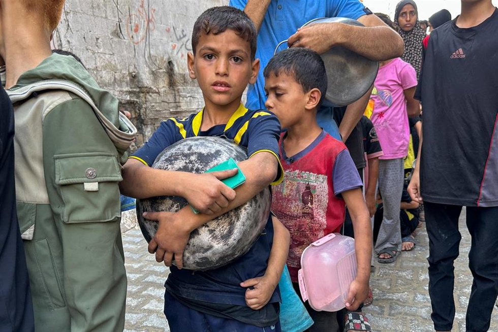 Archivo - Niños palestinos hacen cola para recibir comida en la Franja de Gaza, en medio de los ataques de Israel.