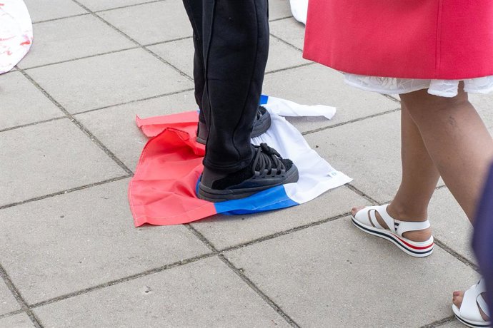 Archivo - May 9, 2025, Warsaw, Poland: A person tramples on a Russian flag during the Victory Day commemoration  at the Soviet military cemetery. On May 9, dozens of Ukrainian activists gathered at the Soviet Military Cemetery to protest against the prese