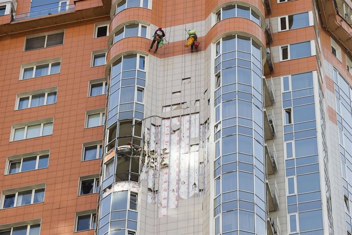 Archivo - Imagen de archivo de dos trabajadores reparando varias ventanas en un edificio alcanzado por un dron ucraniano en Moscú.