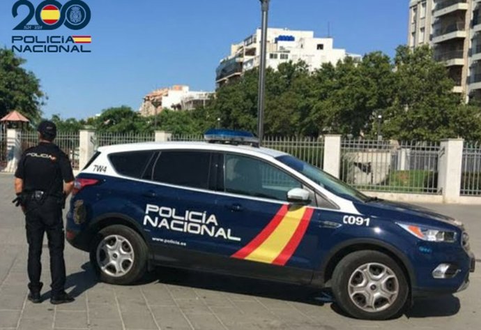 Un agente de la Policía Nacional, junto a una patrulla en Palma.