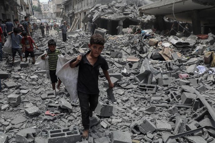 GAZA, 9 de agosto de 2025 -- Crianças caminham sobre escombros após um ataque aéreo israelense na área de Al-Rimal, a oeste da Cidade de Gaza, em 8 de agosto de 2025.