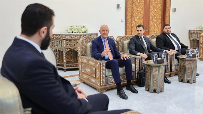 Ao fundo, o presidente de transição da Síria, Ahmed al Shara, em frente à delegação dos EUA liderada pelo enviado especial Tom Barrack.