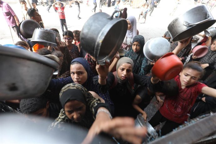 Palestinos esperan a recibir alimentos durante una distribución por parte de una organización caritativa en Al Bureij, en la Franja de Gaza, en medio de la ofensiva de Israel y las restricciones a la entrega de ayuda a la Franja (archivo)