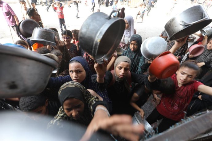 12 de agosto de 2025, Territórios Palestinos, Bureij: Palestinos esperam na fila para receber alimentos de uma cozinha beneficente em meio a uma crise de fome. Foto: Moiz Salhi/APA Images via ZUMA Press Wire/dpa