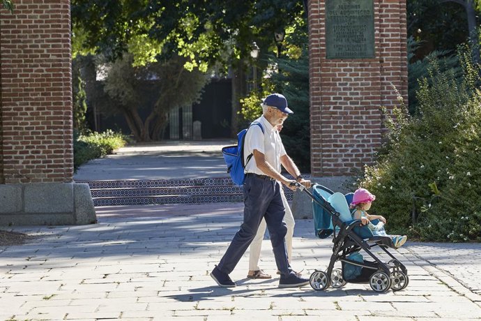 Archivo - Personas mayores pasean con un carrito de bebé