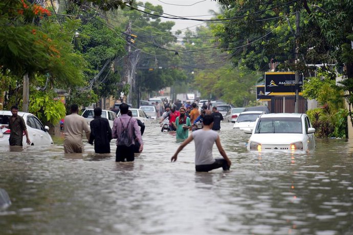 Imagen de archivo de varias personas en una calle anegada por las fuertes inundaciones en Pakisán.
