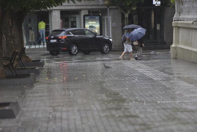 Archivo - Dos personas caminan bajo la lluvia, en Huesca, Aragón (España). 
