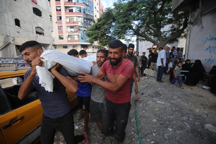 21 de agosto de 2025, Territórios Palestinos, Gaza: Pessoas carregam corpos de palestinos, que foram mortos por fogo israelense enquanto tentavam receber ajuda, de acordo com médicos, no Hospital Al-Shifa, na Cidade de Gaza. Foto: Omar Ashtawy/APA Images 