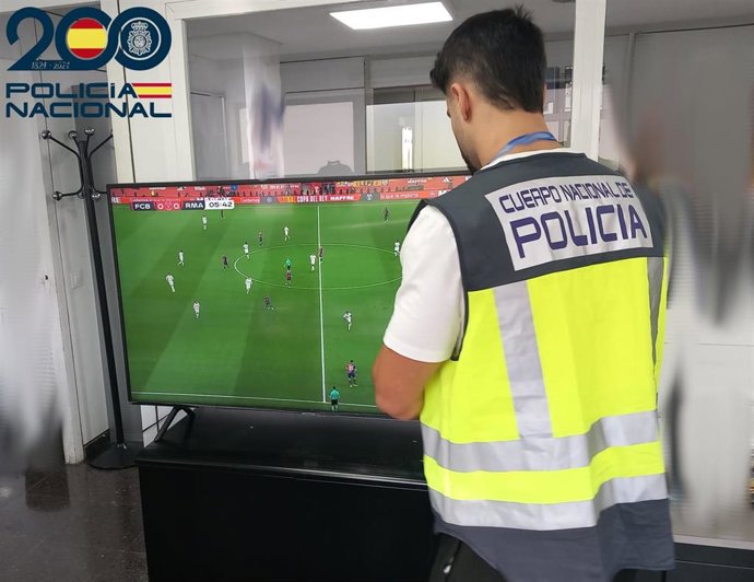 Un agente de la Policía Nacional inspecciona el bar cuyo dueño ha sido denunciado por emitir ilegalmente partidos de La Liga.