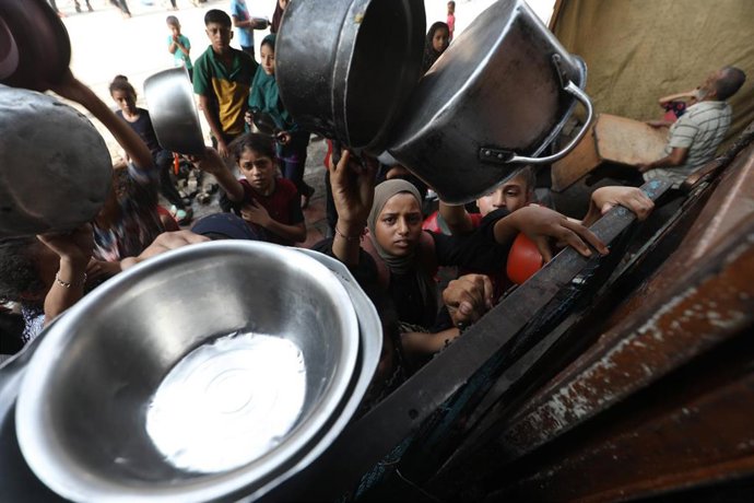 Palestinos esperan recibir alimentos de una organización de ayuda humanitaria en el campamento de refugiados de Al Bureij, en el centro de la Franja de Gaza