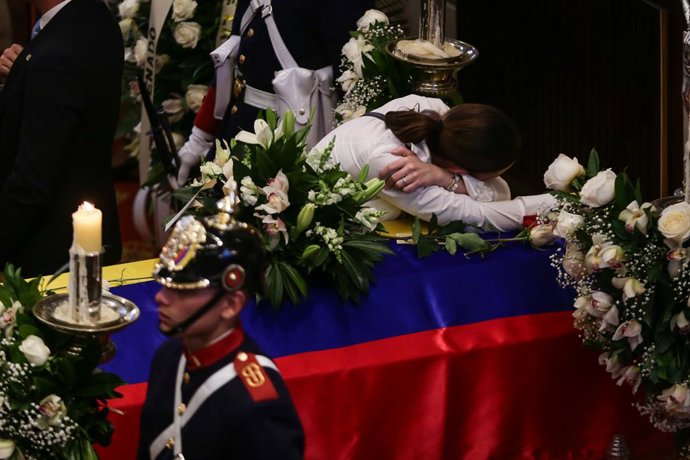 12 de agosto de 2025, Colômbia, Bogotá: Maria Claudia Tarazona (C), esposa do senador da oposição e candidato presidencial assassinado Miguel Uribe Turbay, abraça o caixão do marido durante uma cerimônia de despedida no parlamento. Uribe Turbay, de 39 ano