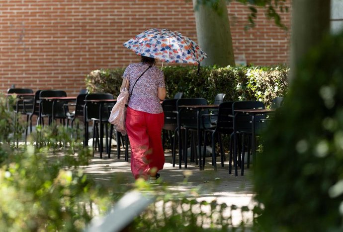 Archivo - Una mujer camina con paraguas