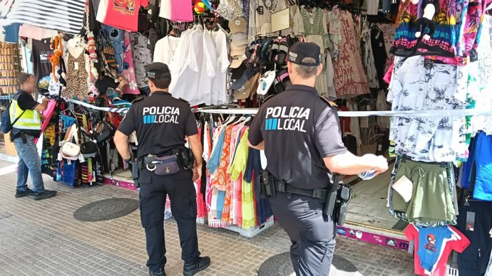 Dos agentes de la Policía Local de Palma inspeccionan un comercio en la Playa de Palma. 