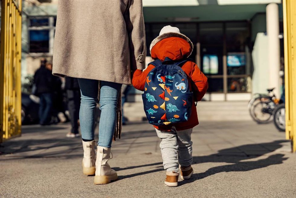 Un niño con mochila entrando al colegio.