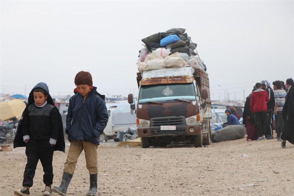 Archivo - Dos niños caminan mientras a su espalda se prepara un convoy de personas para abandonar el campo de Al Hol, en la provincia siria de Hasaka, en el noreste del país 