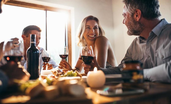 Archivo - Grupo de personas en una comida tomando una copa de vino.