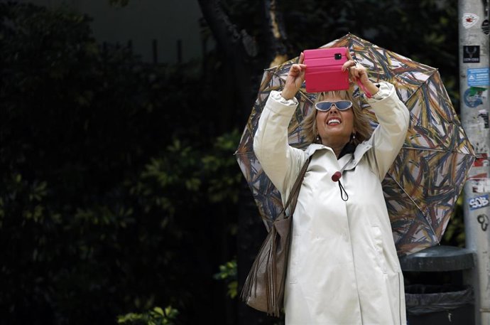 Archivo - Una persona se protege de la lluvia.