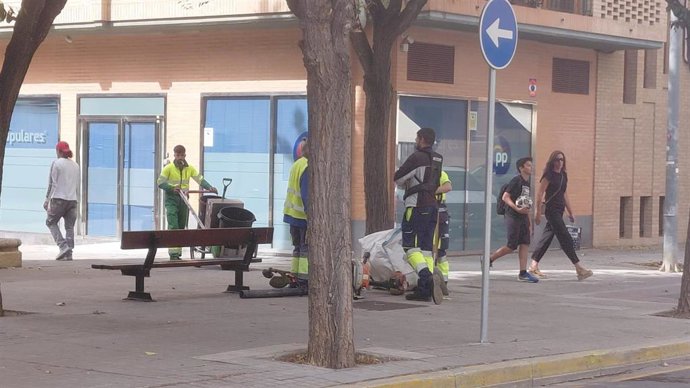 Operarios limpian en el entorno de la sede vandalizada del PP en Huesca.