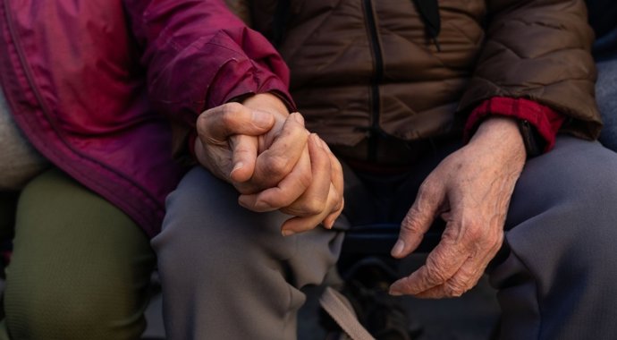 Dos personas mayores se cogen de la mano.