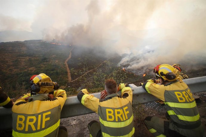 Bombeiros observam o incêndio florestal, 24 de agosto de 2025, em La Baña, Encinedo, La Cabrera, León, Castilla y León (Espanha). A evolução do incêndio florestal proveniente de Porto (Zamora) foi "favorável" durante a noite, embora tenha funcionado como 