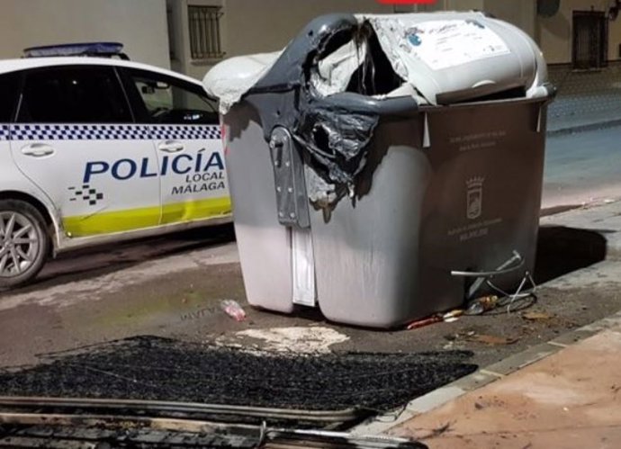Archivo - Imagen de archivo de un coche de la Policía Local de Málaga y un contenedor quemado.